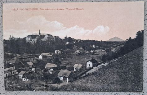 obrázek domu s okolní zástavbou a zámkem v pozadí