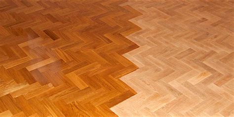 Detail dřevěné parketové podlahy ve tvaru rybí kosti s patinou.