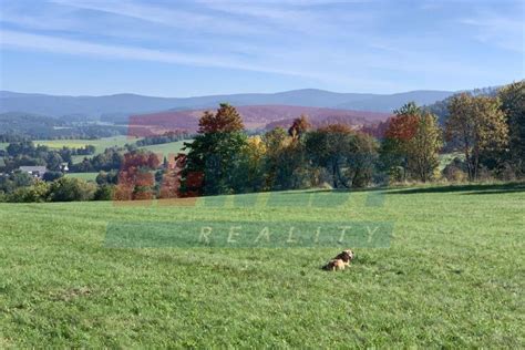 Vizualizace nebo fotografie mírně svažitého pozemku s výhledem do krajiny.
