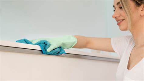 Detailní záběr na utírání prachu z povrchu mikrovláknovým hadříkem